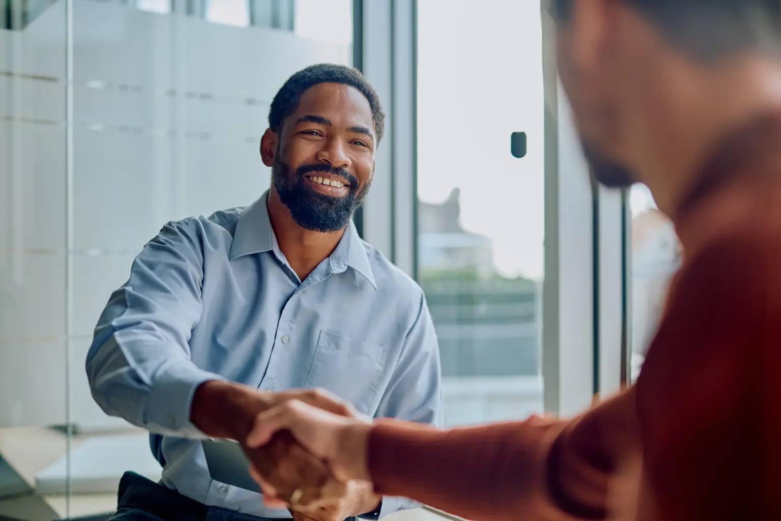 Two men shaking hands in an office - Man and woman shaking hands - trusted financial advice from Futures Assured